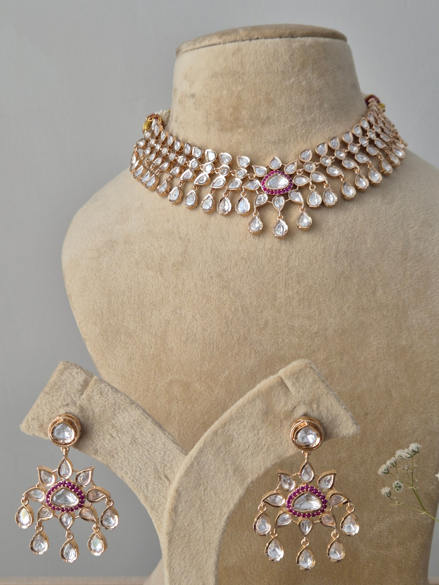 Pair of matching Rosalie American Diamond drop earrings with ruby-red centers and teardrop accents, displayed alongside a coordinating statement necklace by naitri.in
