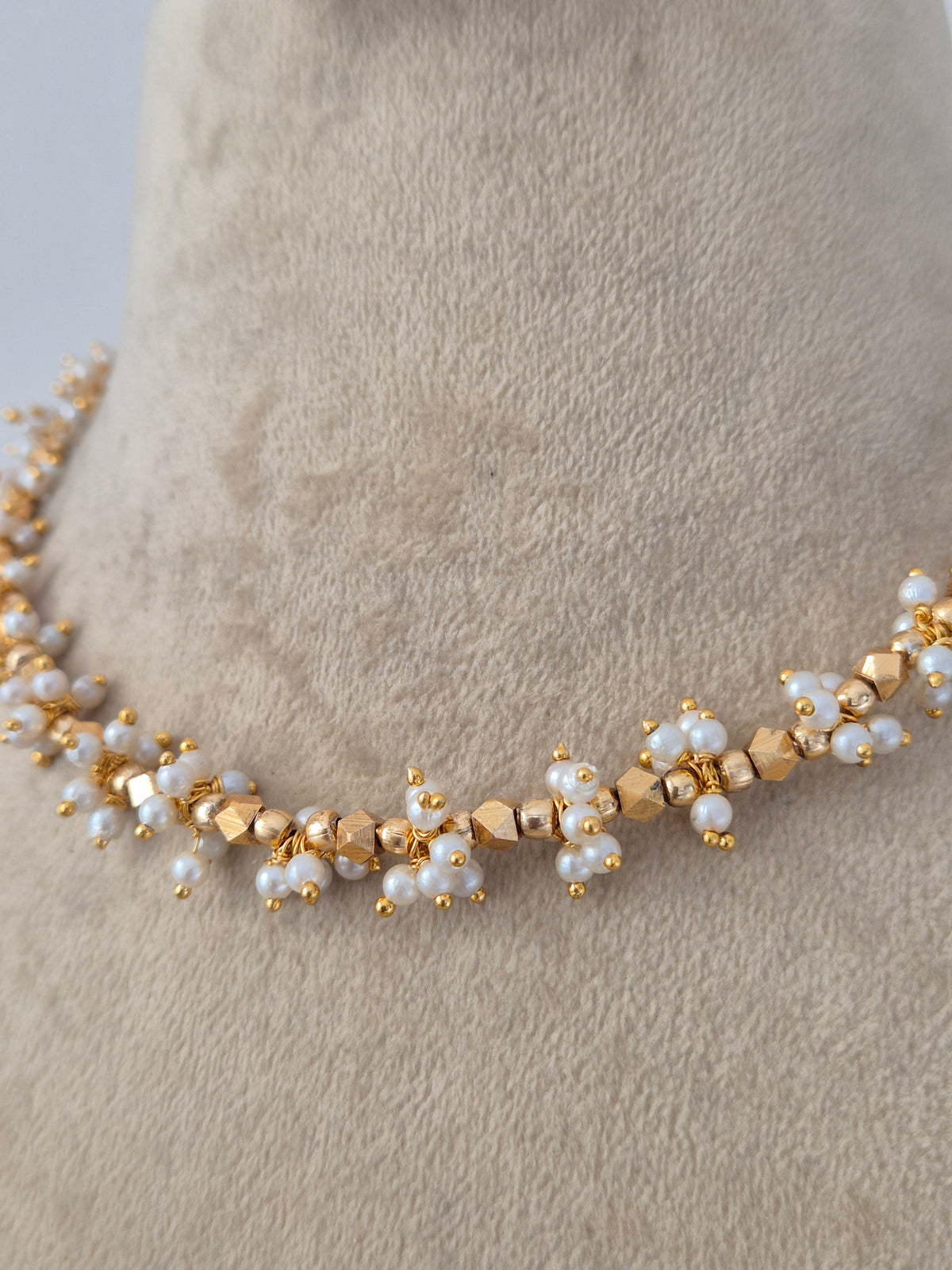Ornate Designer Floral Necklace and Studs presented on a display bust, emphasizing the delicate petal details, rich golden texture, and timeless cultural appeal by Naitri.in 