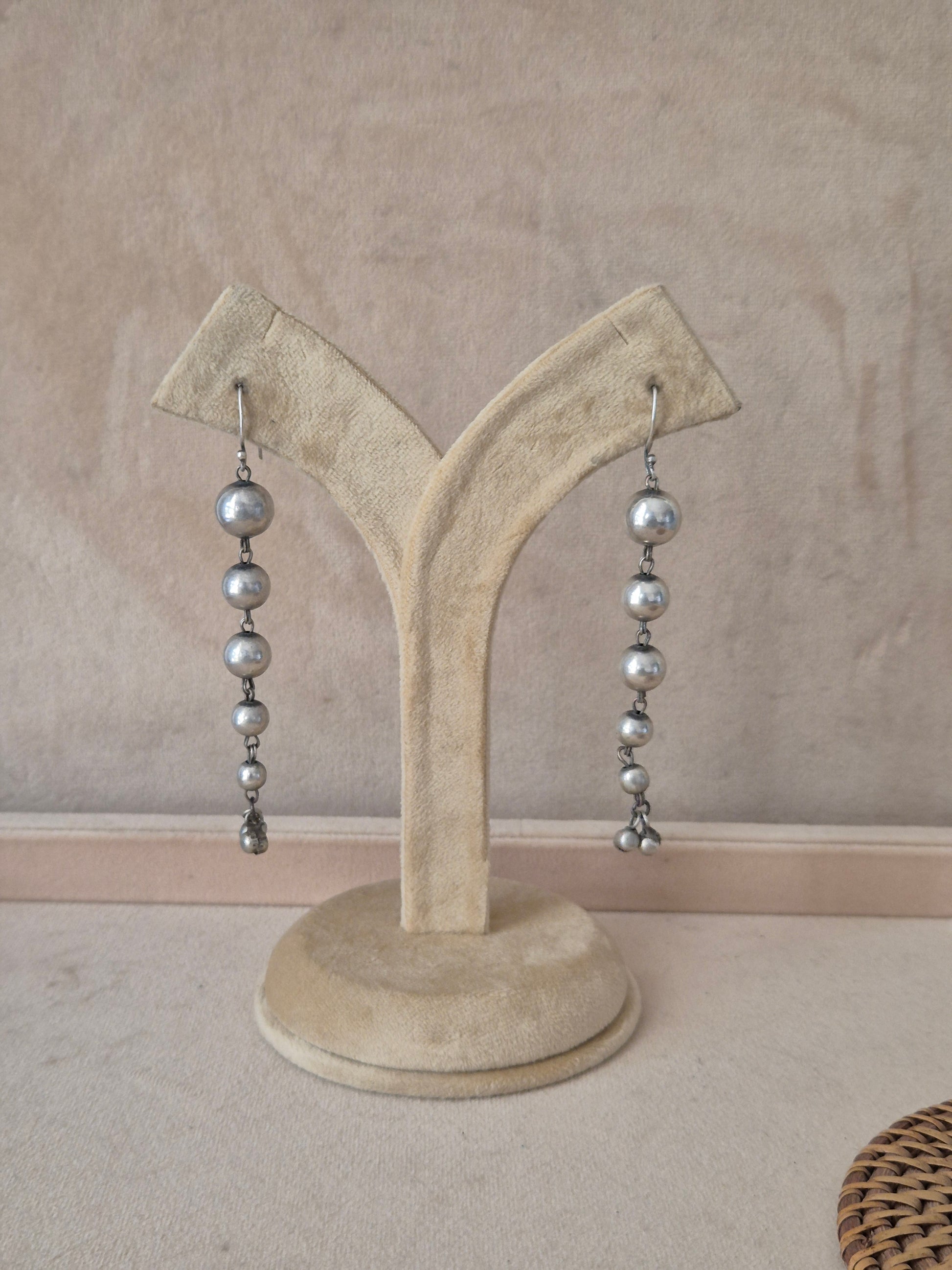Pair of Sabina silver-toned long dangle earrings featuring a vertical string of polished metallic beads by naitri.in