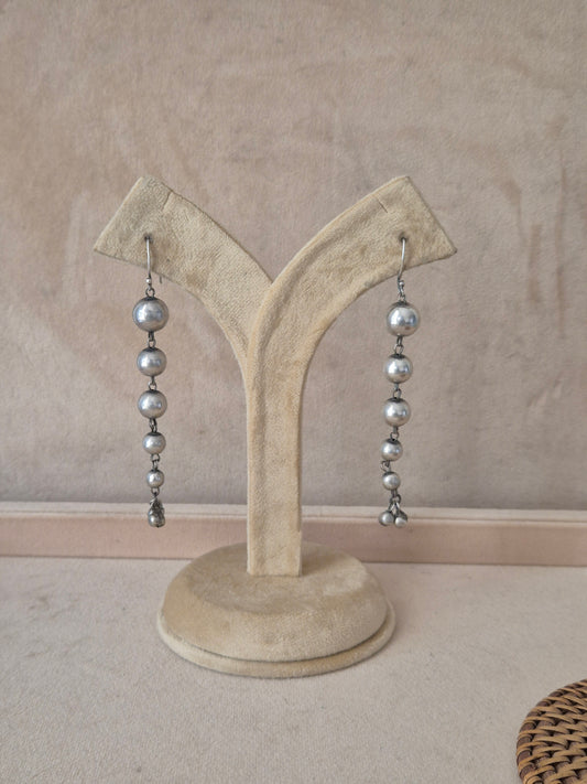 Pair of Sabina silver-toned long dangle earrings featuring a vertical string of polished metallic beads by naitri.in