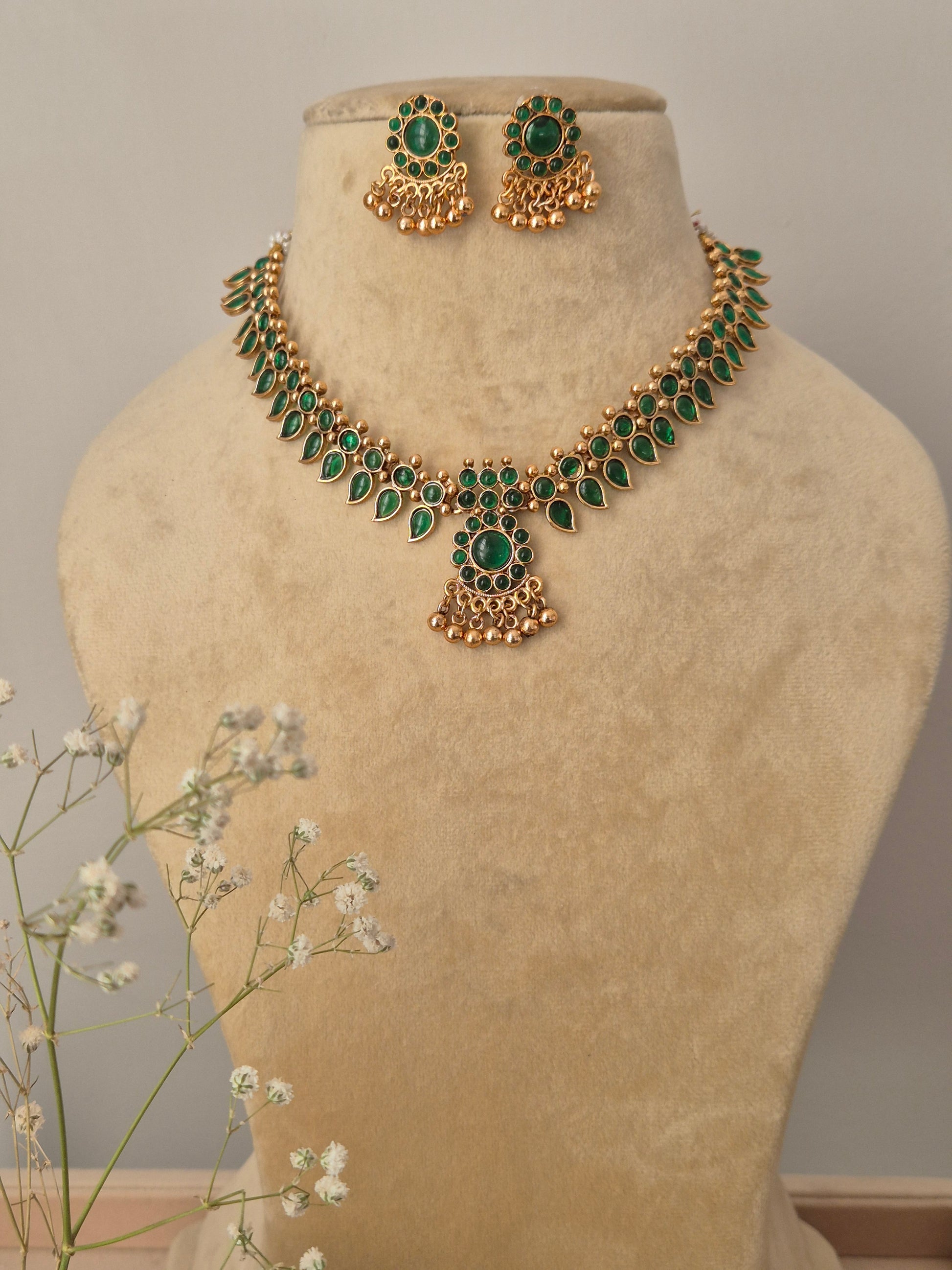 Gold-plated choker necklace featuring intricate green stonework with matching stud earrings by naitri.in