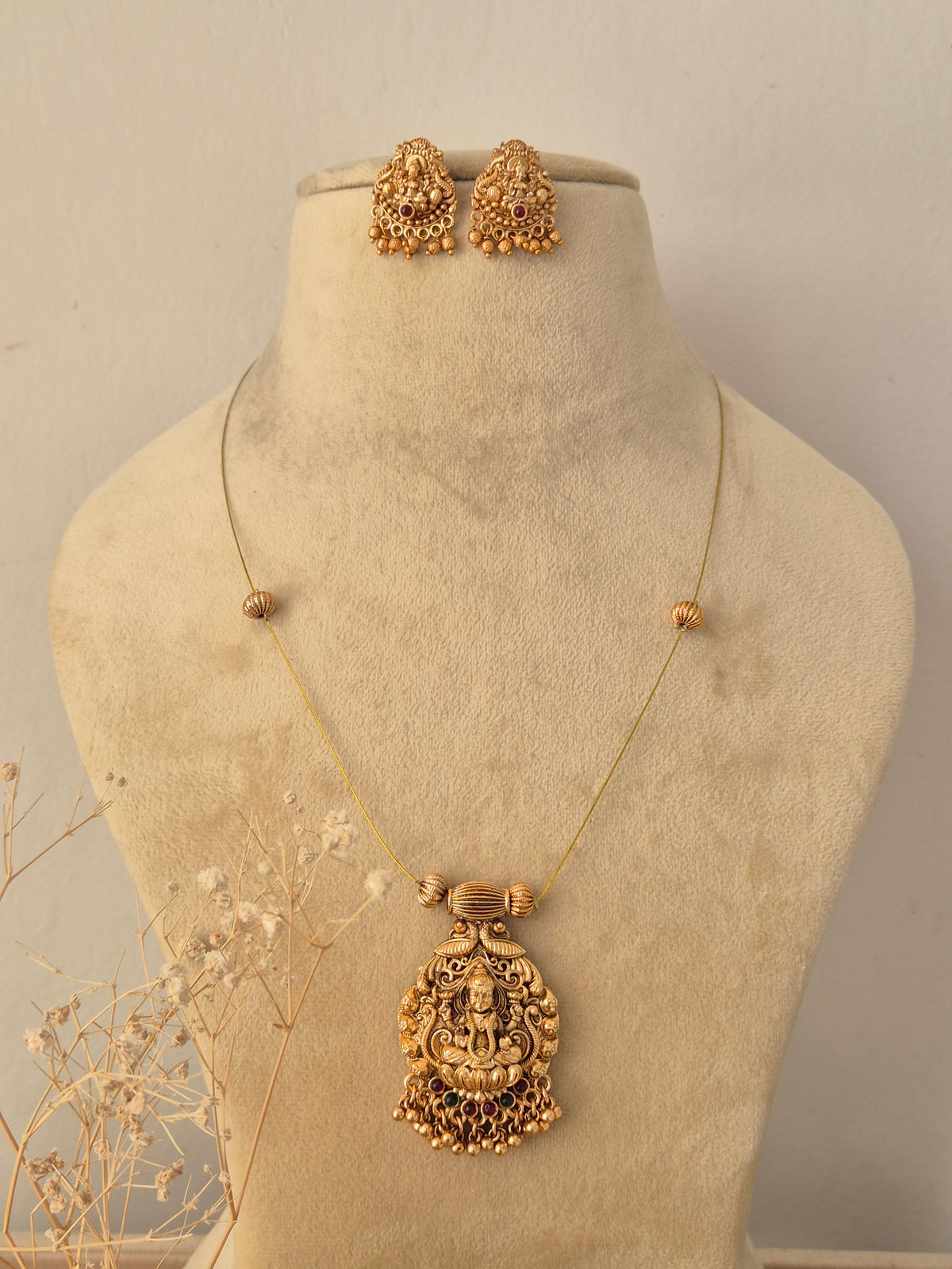 Saisha Necklace Set featuring a traditional gold temple pendant with gemstone accents and matching stud earrings by Naitri.in