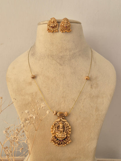Saisha Necklace Set featuring a traditional gold temple pendant with gemstone accents and matching stud earrings by Naitri.in