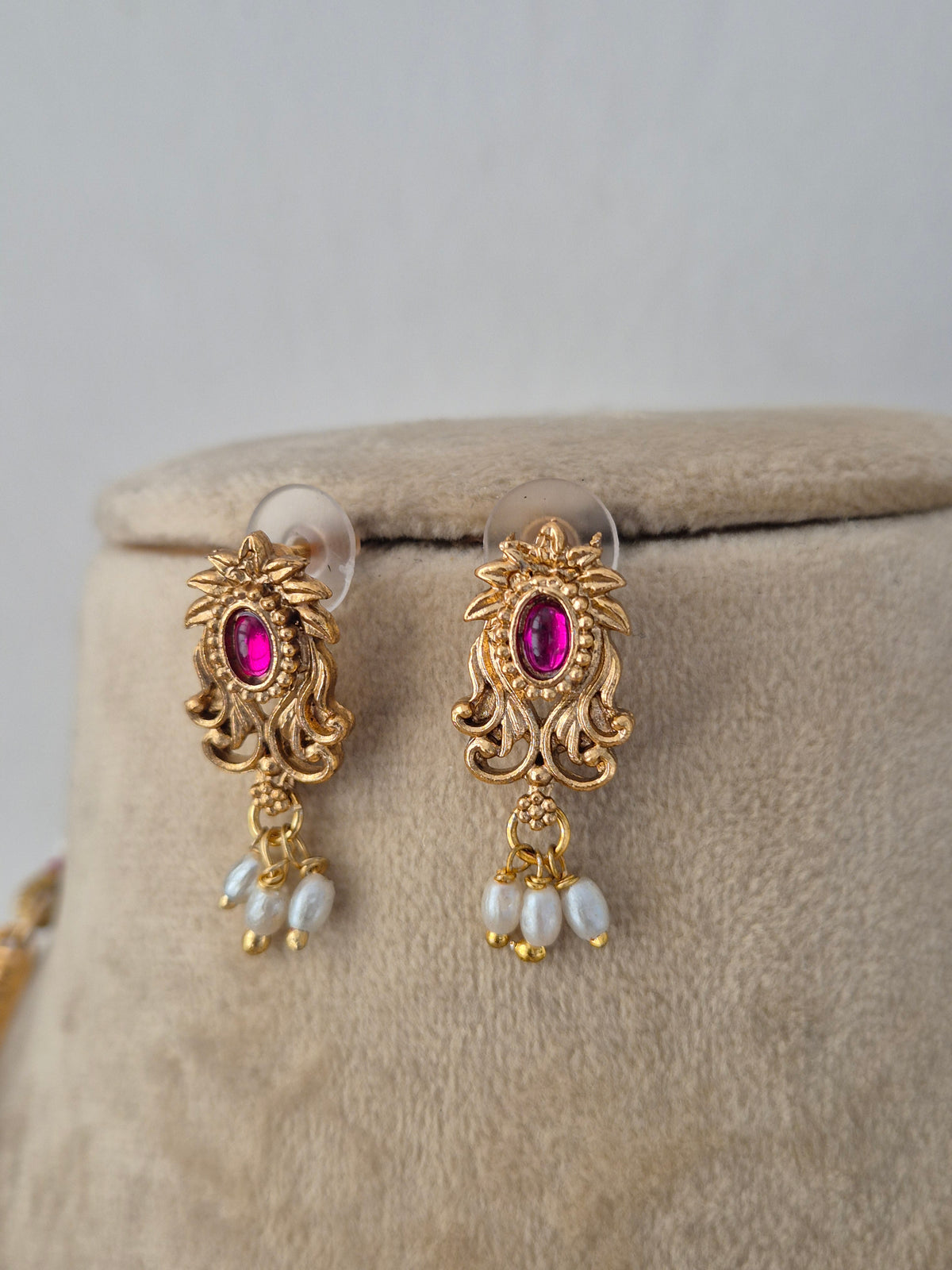 Santoshi traditional handcrafted earrings featuring intricate traditional floral motifs embedded with red stones with dangling white pearls by naitri.in