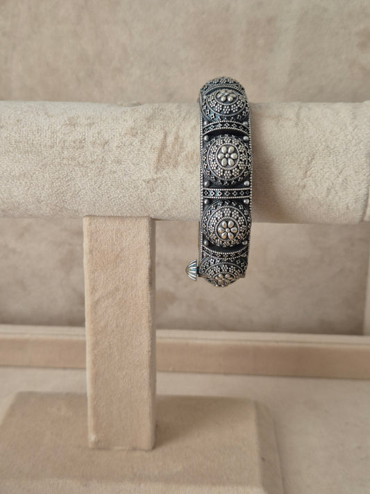 Intricate silver oxidized Shilpa bangle with detailed floral and leaf engraving by naitri.in