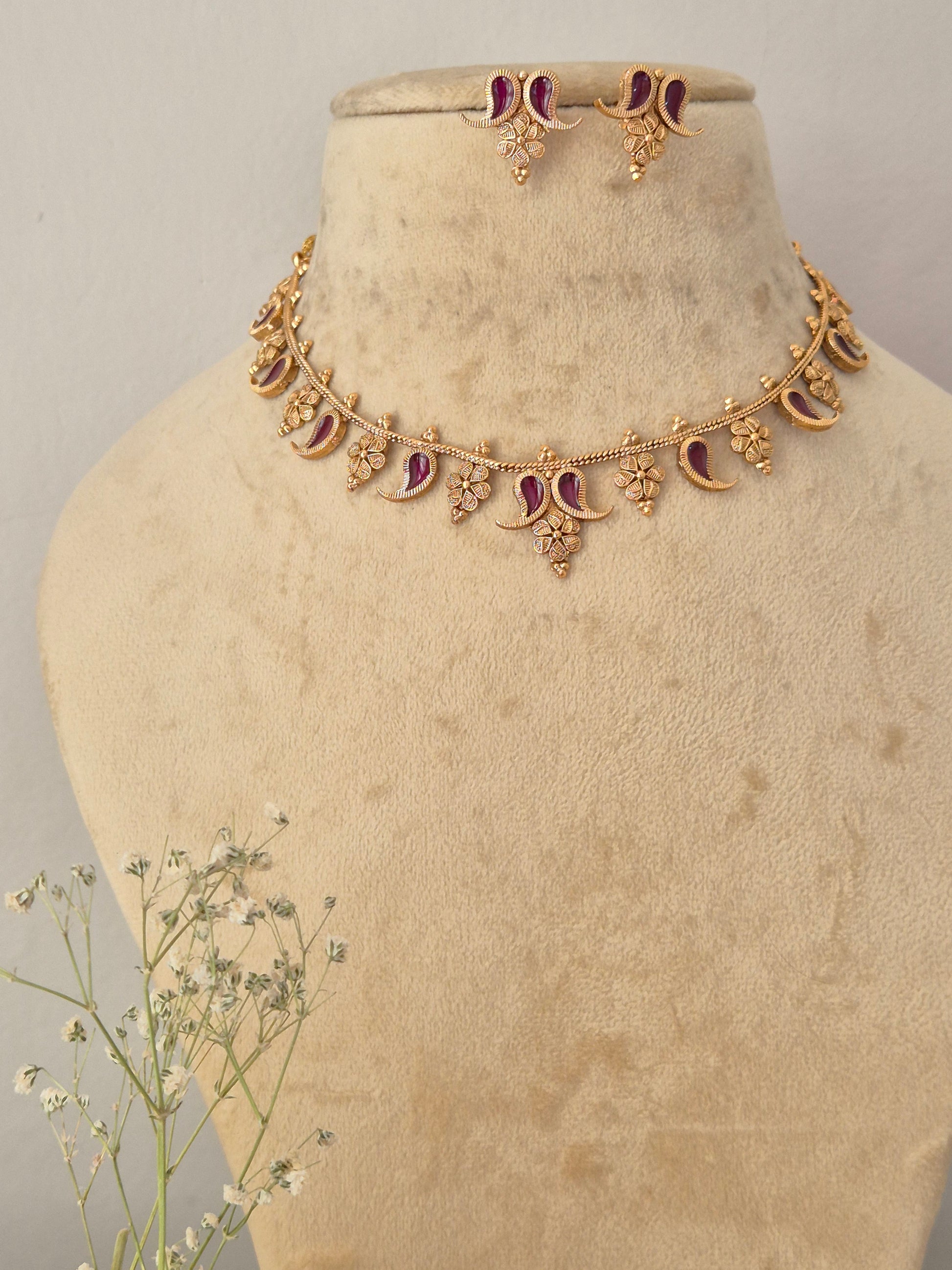 Gold-toned traditional Indian necklace and matching small dangle earrings set features intricate crescent and floral motifs inset with deep wine-colored gemstones, accented with matching earrings by naitri.in