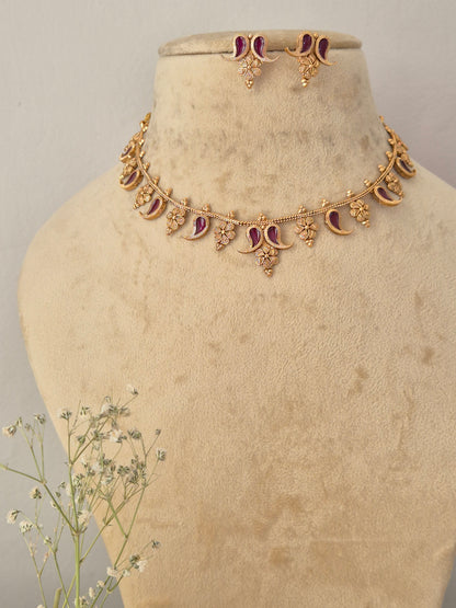 Gold-toned traditional Indian necklace and matching small dangle earrings set features intricate crescent and floral motifs inset with deep wine-colored gemstones, accented with matching earrings by naitri.in