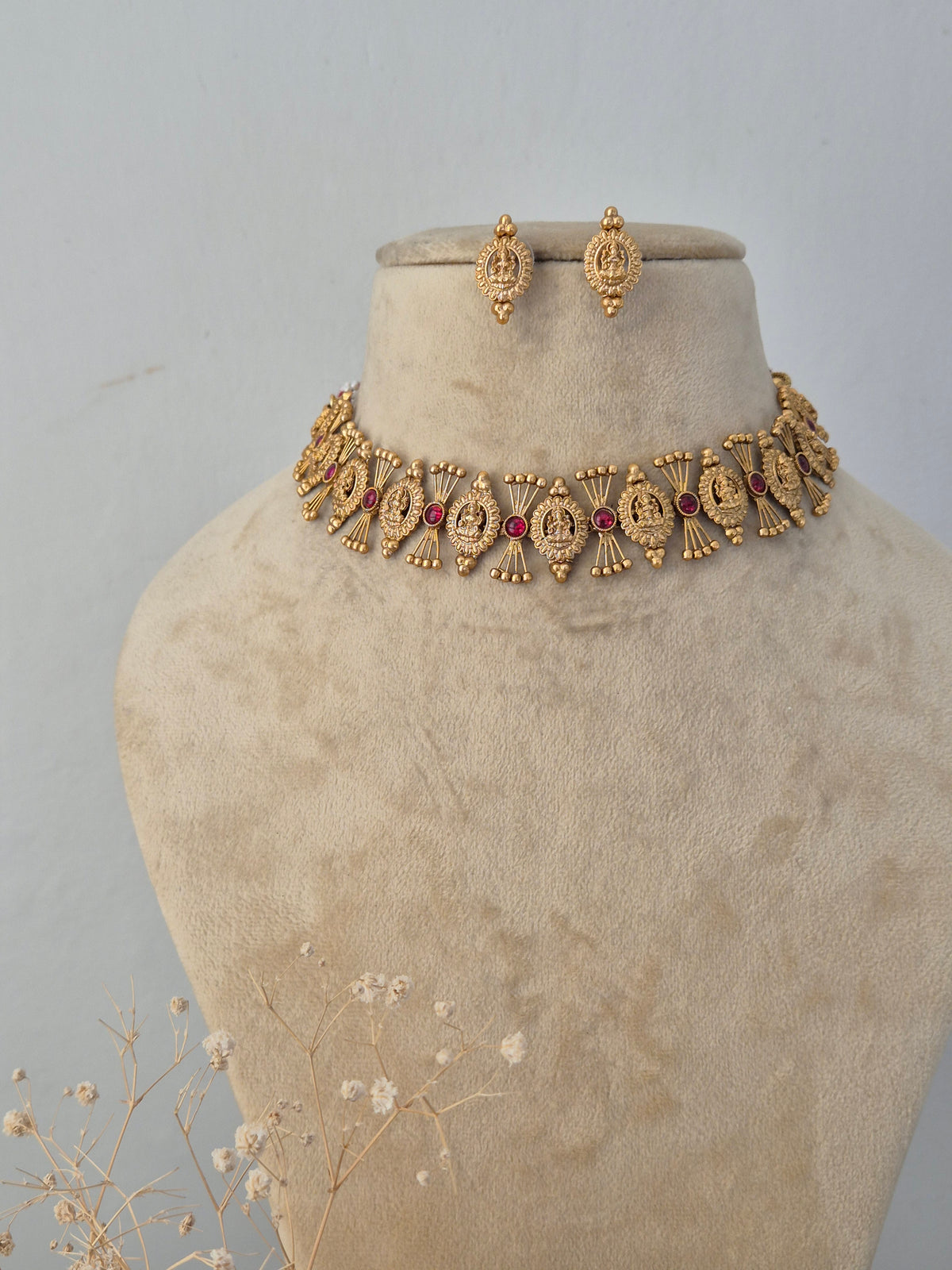 Traditional Indian gold necklace set with red stone embellishments and matching jhumka earrings by Naitri.in