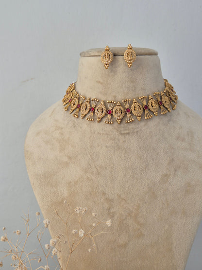 Traditional Indian gold necklace set with red stone embellishments and matching jhumka earrings by Naitri.in