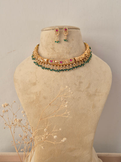 Simmi Necklace Set featuring traditional gold temple motifs with vibrant ruby stone accents and matching earrings by Naitri.in