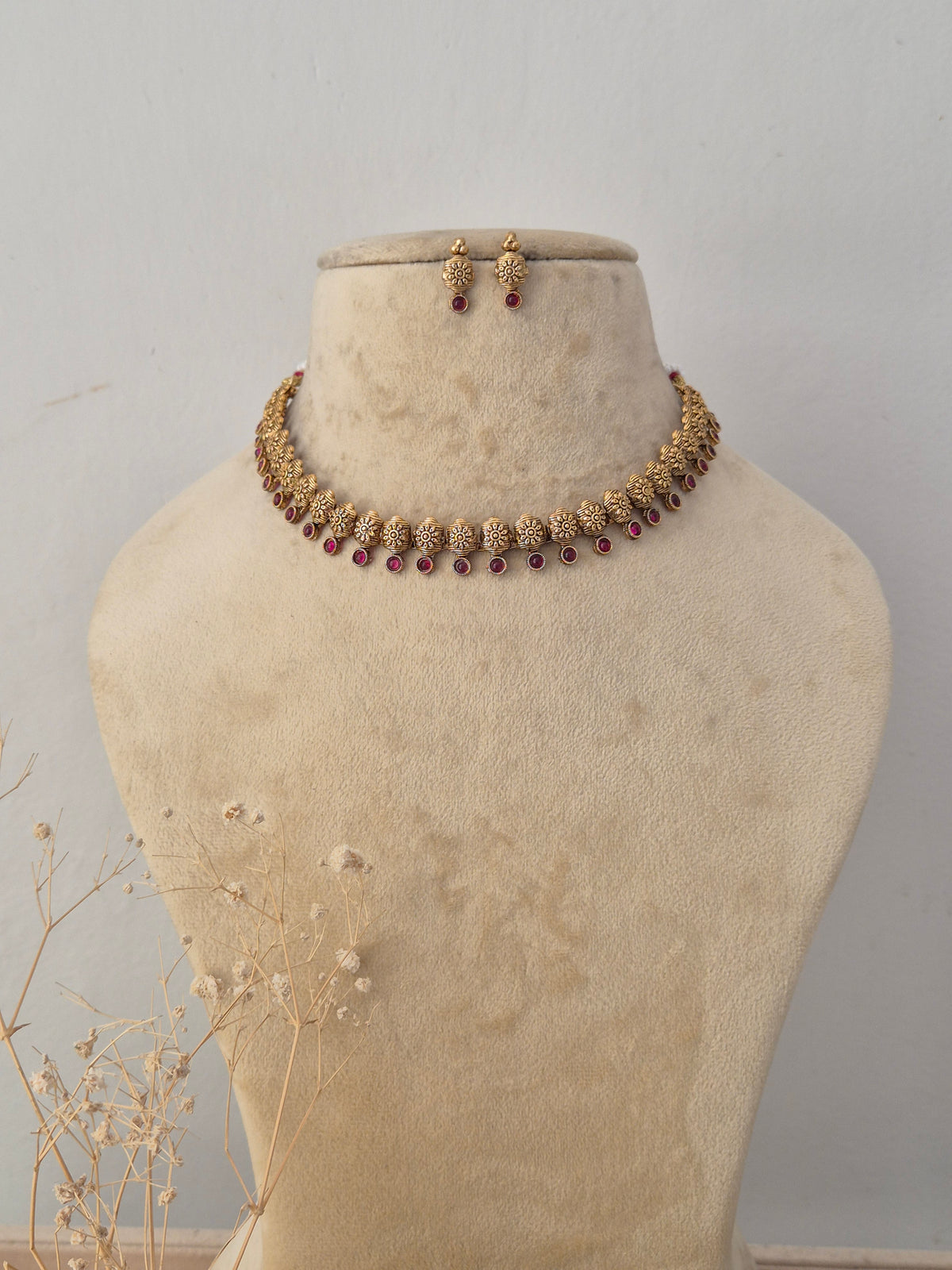 Simran Necklace Set featuring traditional gold temple motifs with vibrant ruby gemstone accents and matching earrings by Naitri.in 