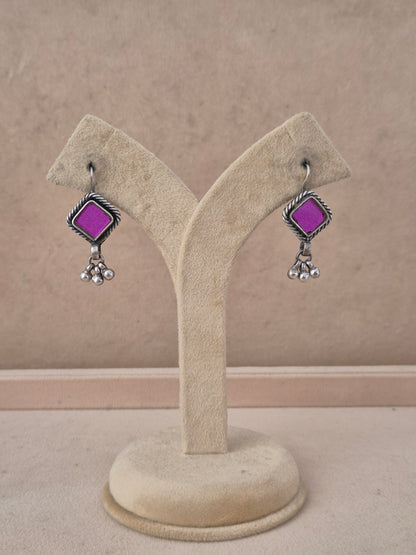 A pair of silver-toned dangle earrings with bright purple square stones, by naitri.in