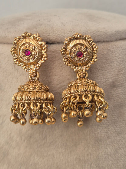 An ornate gold-toned traditional Indian jhumka earring decorated with pink gemstone accents for festive wear by naitri.in