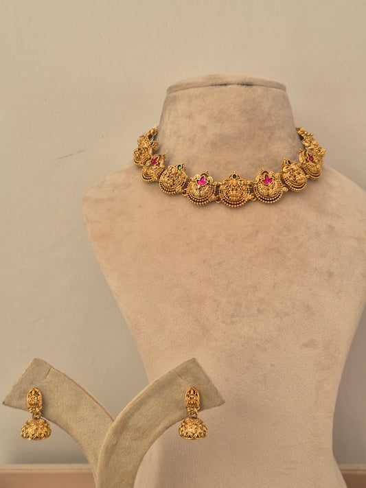 Gold-toned traditional jewelry set including a necklace with ornate circular motifs and pink stone accents, plus matching earrings  by naitri.in
