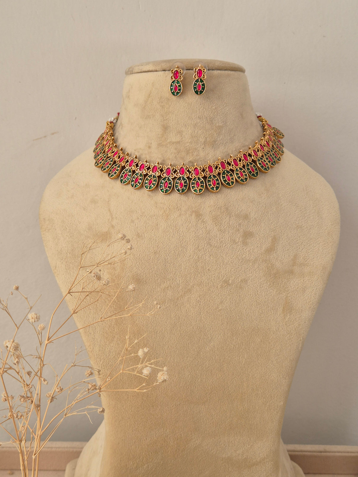 Suman Necklace Set in antique gold finish featuring ruby and emerald stones with matching stud earrings by Naitri.in