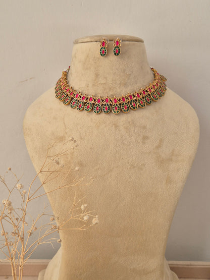 Suman Necklace Set in antique gold finish featuring ruby and emerald stones with matching stud earrings by Naitri.in