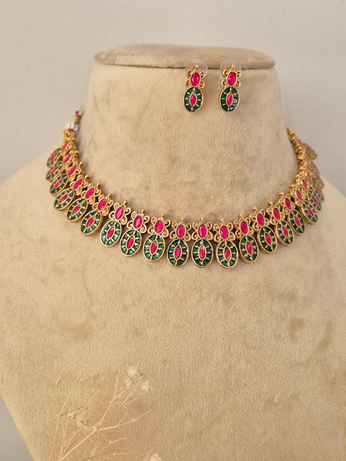Close-up product view of a detailed gold and gemstone necklace and matching stud earrings