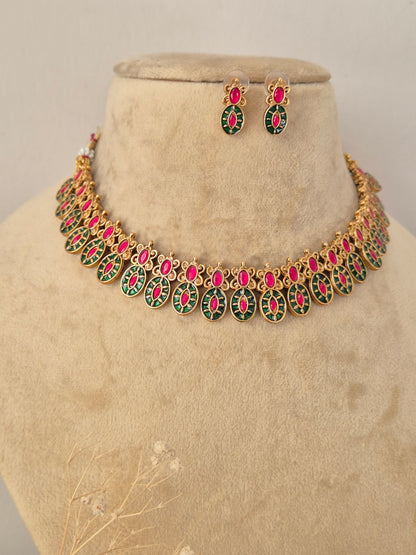 Close-up product view of a detailed gold and gemstone necklace and matching stud earrings