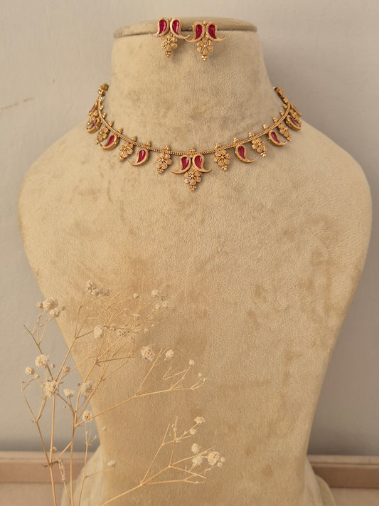 Gold-toned traditional Indian necklace and matching small dangle earrings set features intricate crescent and floral motifs inset with red-colored gemstones, accented with matching earrings by naitri.in