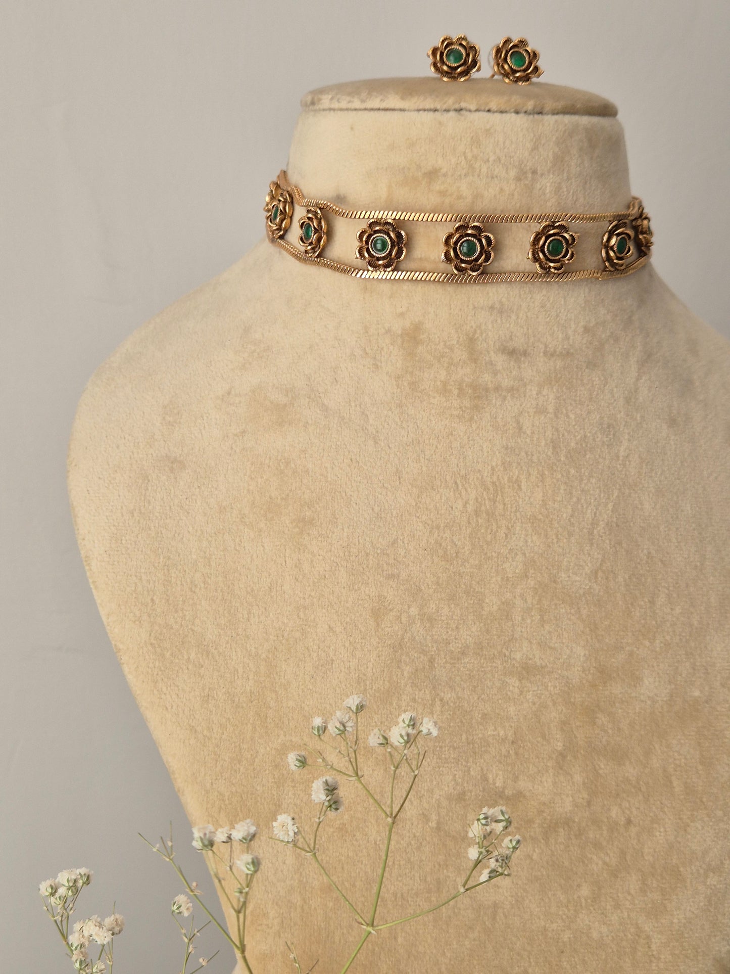 gold and Green Stone Set: An artisanal brass choker with floral detailing and coordinating stud earrings by naitri.in