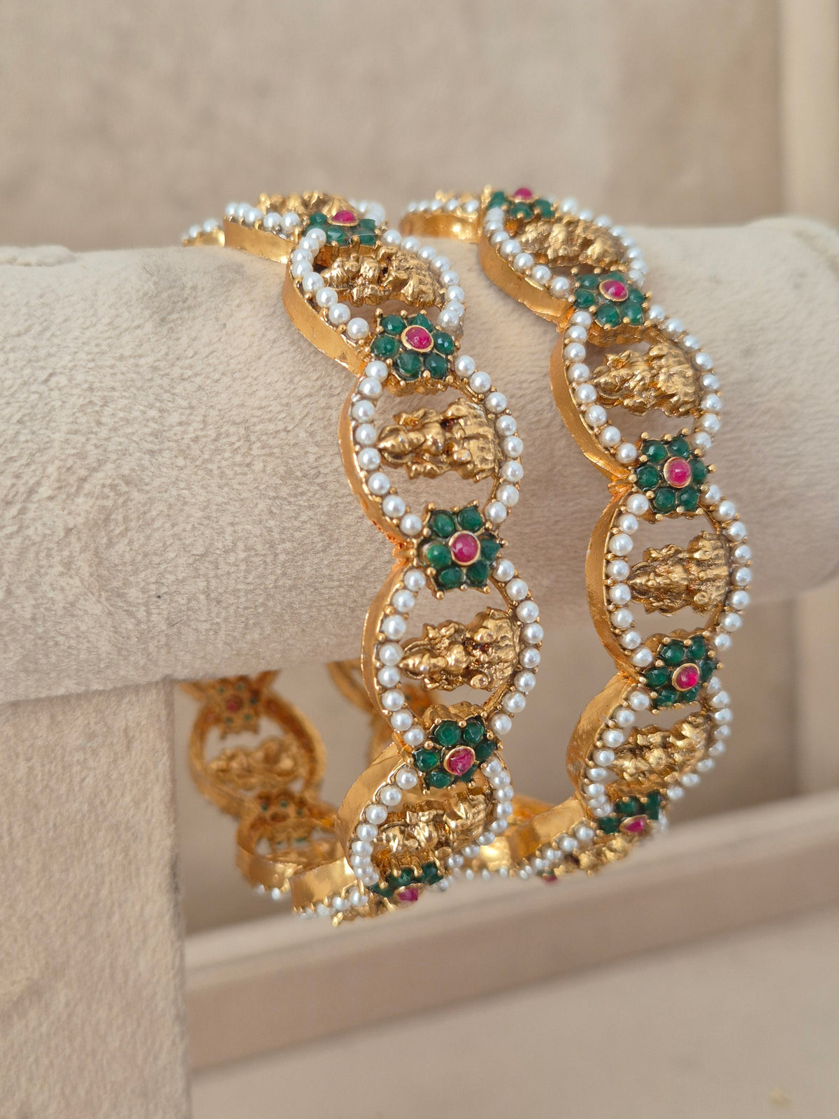 Royal Indian gold-plated bangles embellished with vibrant red and green stones and pearl borders for festive and bridal wear by naitri.in