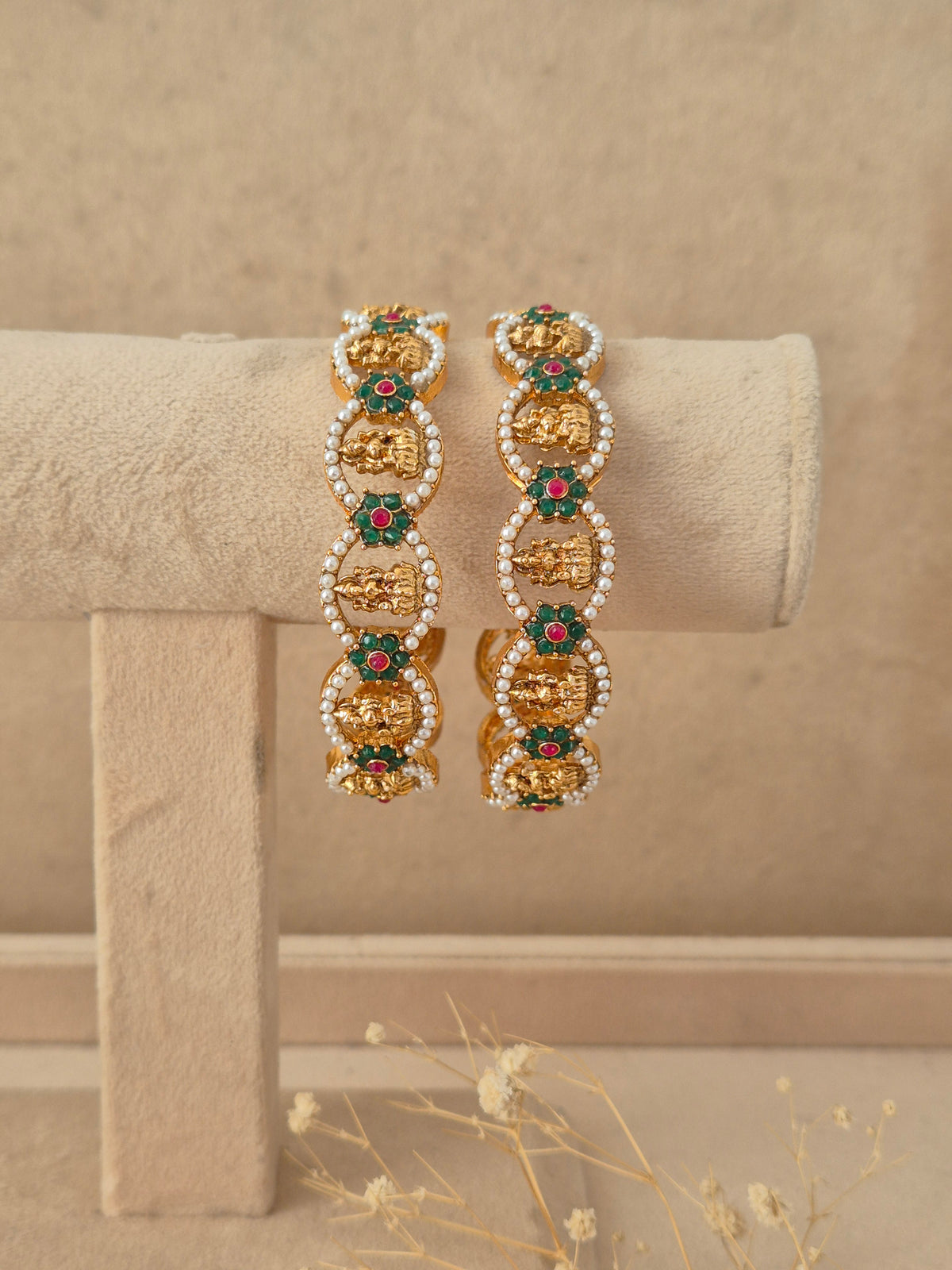 Set of 2 gold-plated bangles featuring oval-shaped motifs studded with green and pink gemstones surrounded by tiny white pearls by naitri.in