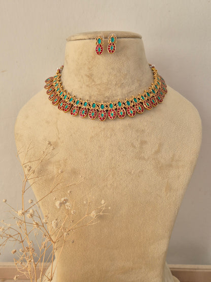 Tara Necklace Set featuring traditional gold temple motifs with vibrant ruby and turquoise stone accents and matching earrings by Naitri.in