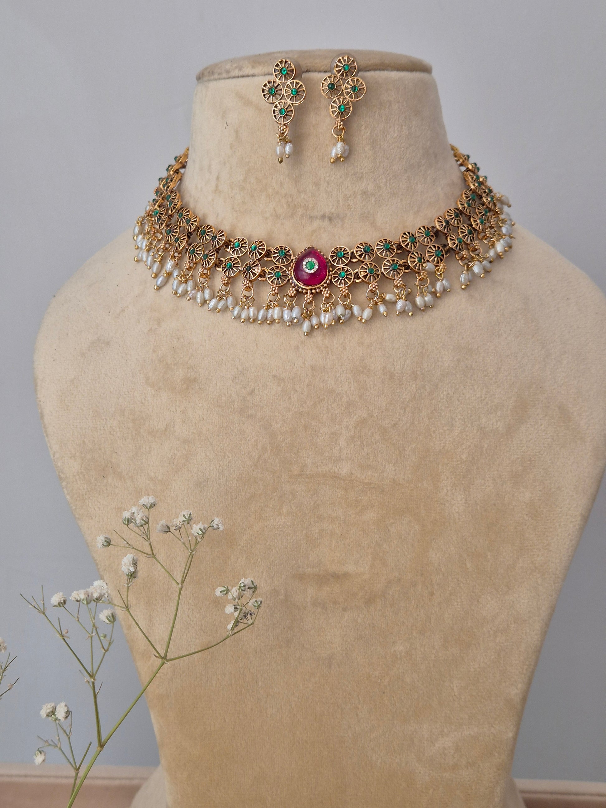 A handcrafted gold-polished brass strand necklace featuring textured gold beads and a central ruby-red stone pendant,  by naitri.in