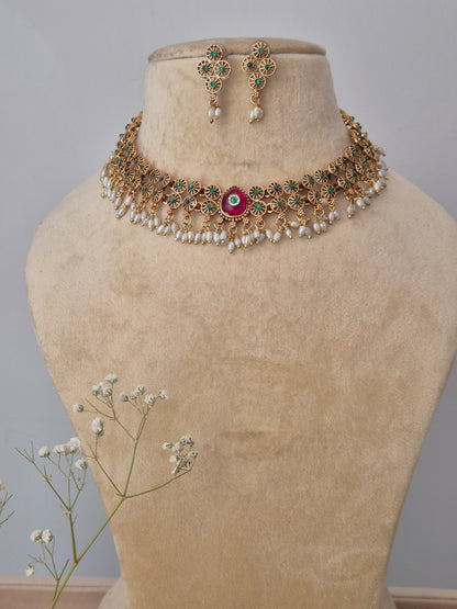 A handcrafted gold-polished brass strand necklace featuring textured gold beads and a central ruby-red stone pendant,  by naitri.in