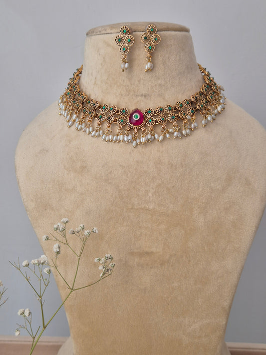 A handcrafted gold-polished brass strand necklace featuring textured gold beads and a central ruby-red stone pendant,  by naitri.in