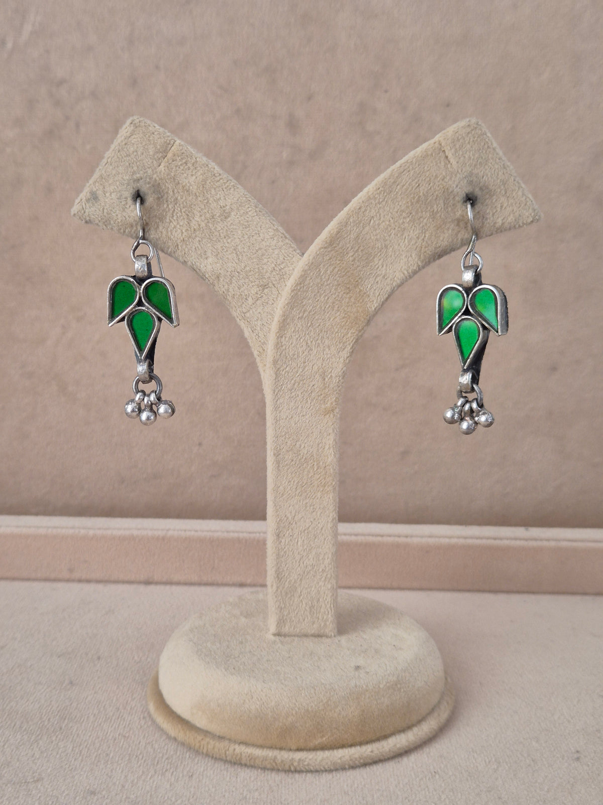 Pair of green leaf-shaped glass drop earrings with silver bead detail. Tina green glass dangle earrings with silver embellishments by naitri.in