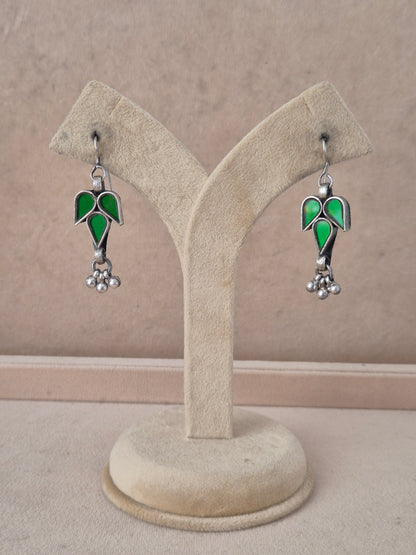 Pair of green leaf-shaped glass drop earrings with silver bead detail. Tina green glass dangle earrings with silver embellishments by naitri.in