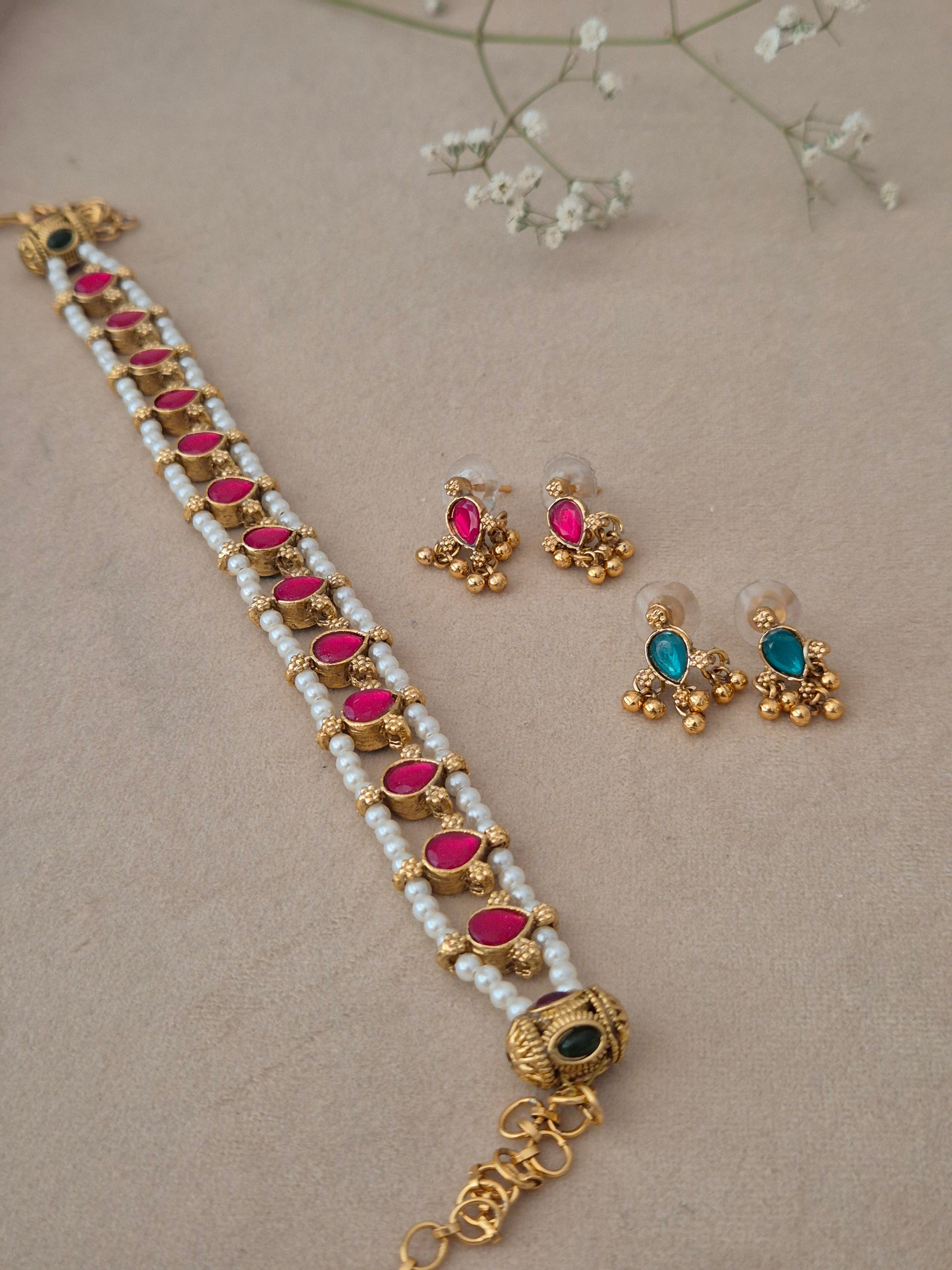 A multi-strand white pearl choker necklace with teardrop-shaped pink stones and matching stud earrings by naitri.in