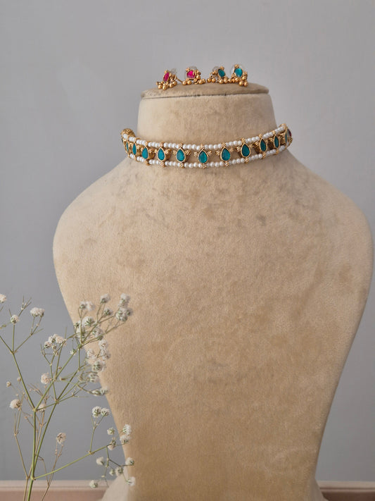 A multi-strand white pearl choker necklace with teardrop-shaped turquoise-blue stones and matching stud earrings by naitri.in