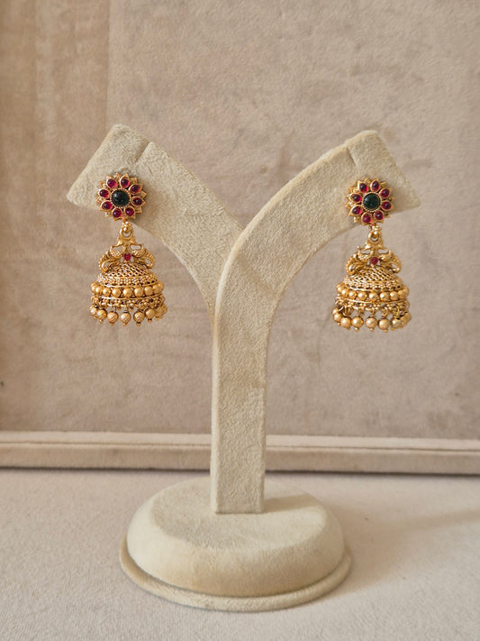 Gold-toned Jhumka earrings with intricate floral studs featuring red and green gemstones by naitri.in