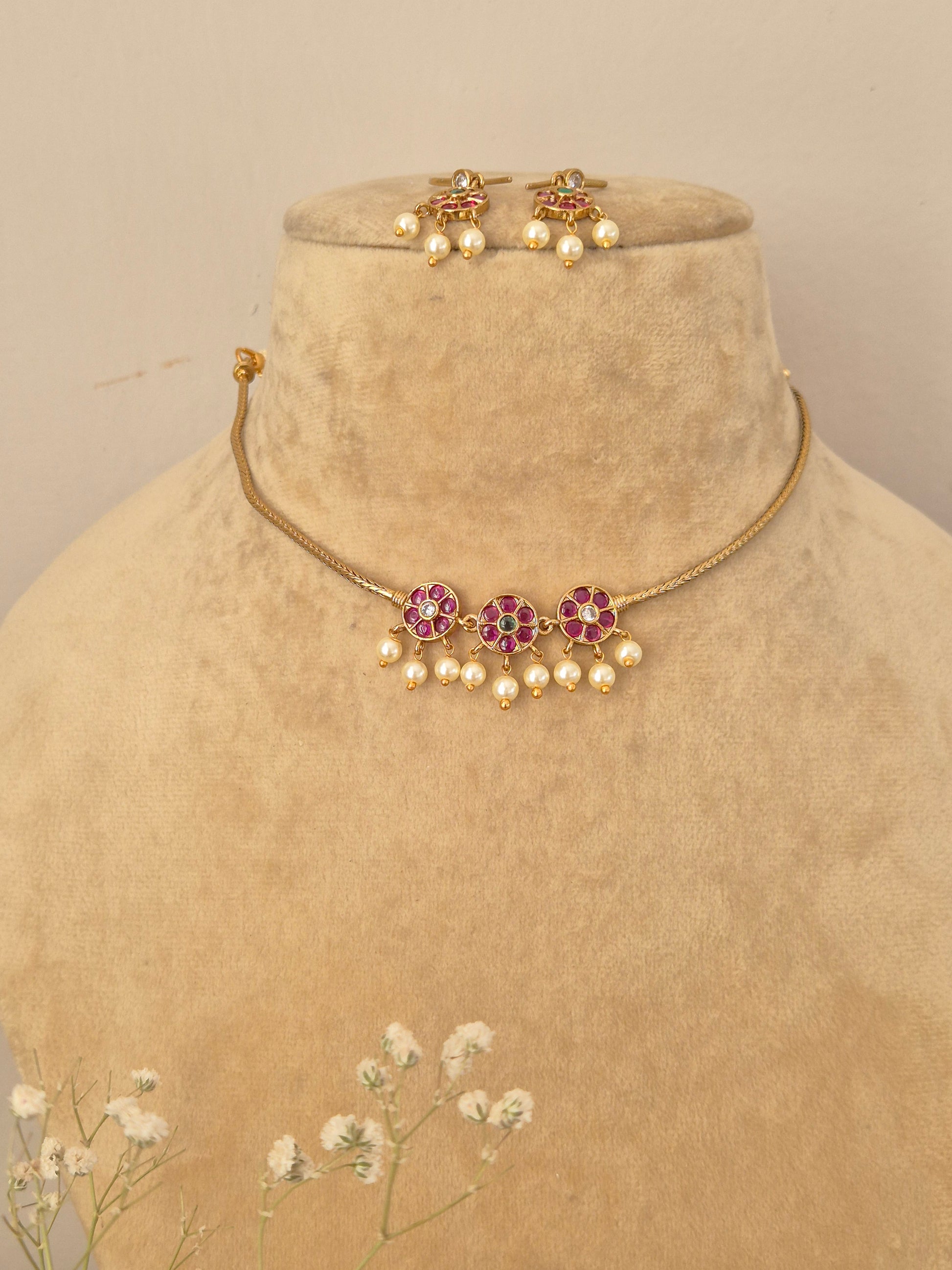 Handcrafted gold choker necklace and matching drop earrings featuring pink and green floral stones with seed pearl fringes by naitri.in