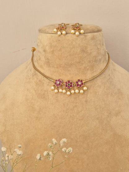 Handcrafted gold choker necklace and matching drop earrings featuring pink and green floral stones with seed pearl fringes by naitri.in