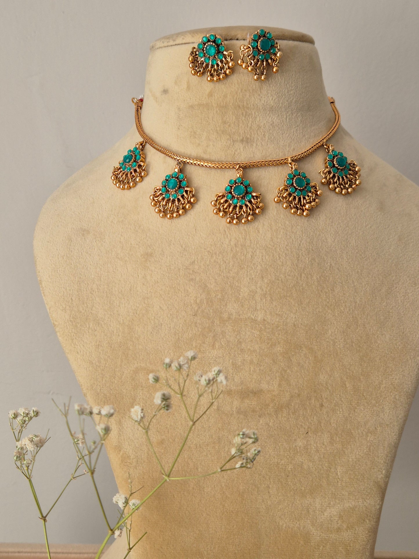 Handcrafted gold-polished brass choker featuring turquoise-green stone pendants with gold bead fringes and matching turquoise stud earrings by naitri.in