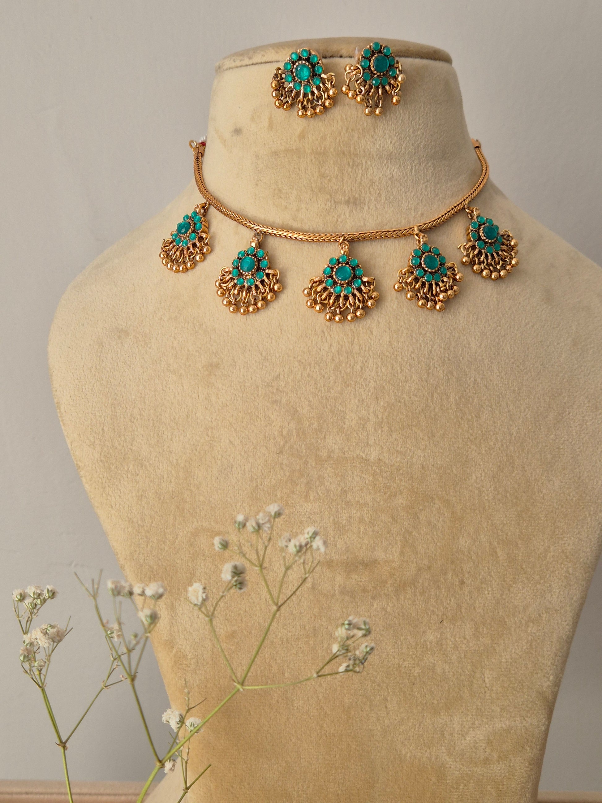 Handcrafted gold-polished brass choker featuring turquoise-green stone pendants with gold bead fringes and matching turquoise stud earrings by naitri.in