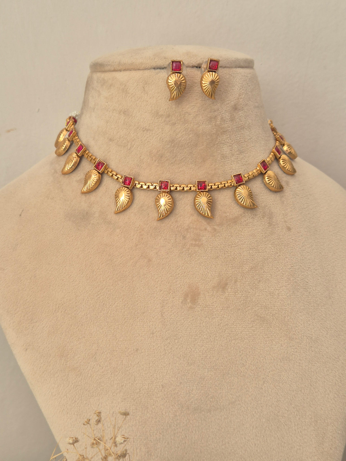 Traditional gold choker necklace and stud earrings set with red gemstone detailing  by naitri.in