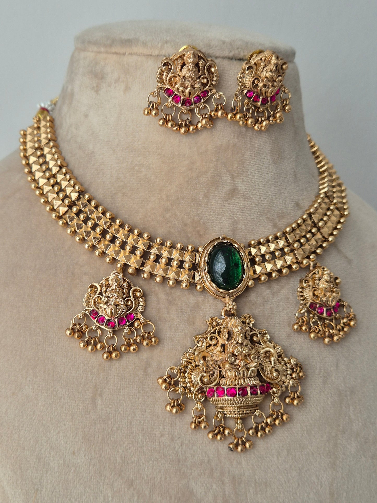 Traditional temple jewellery with big spherical green emerald in the middle of necklace by naitri.in