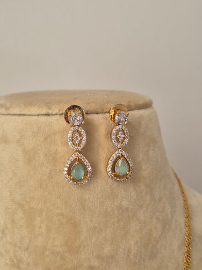 Minimalist golden necklace featuring a central cluster of green stones in a teardrop setting with matching stud earrings by naitri.in