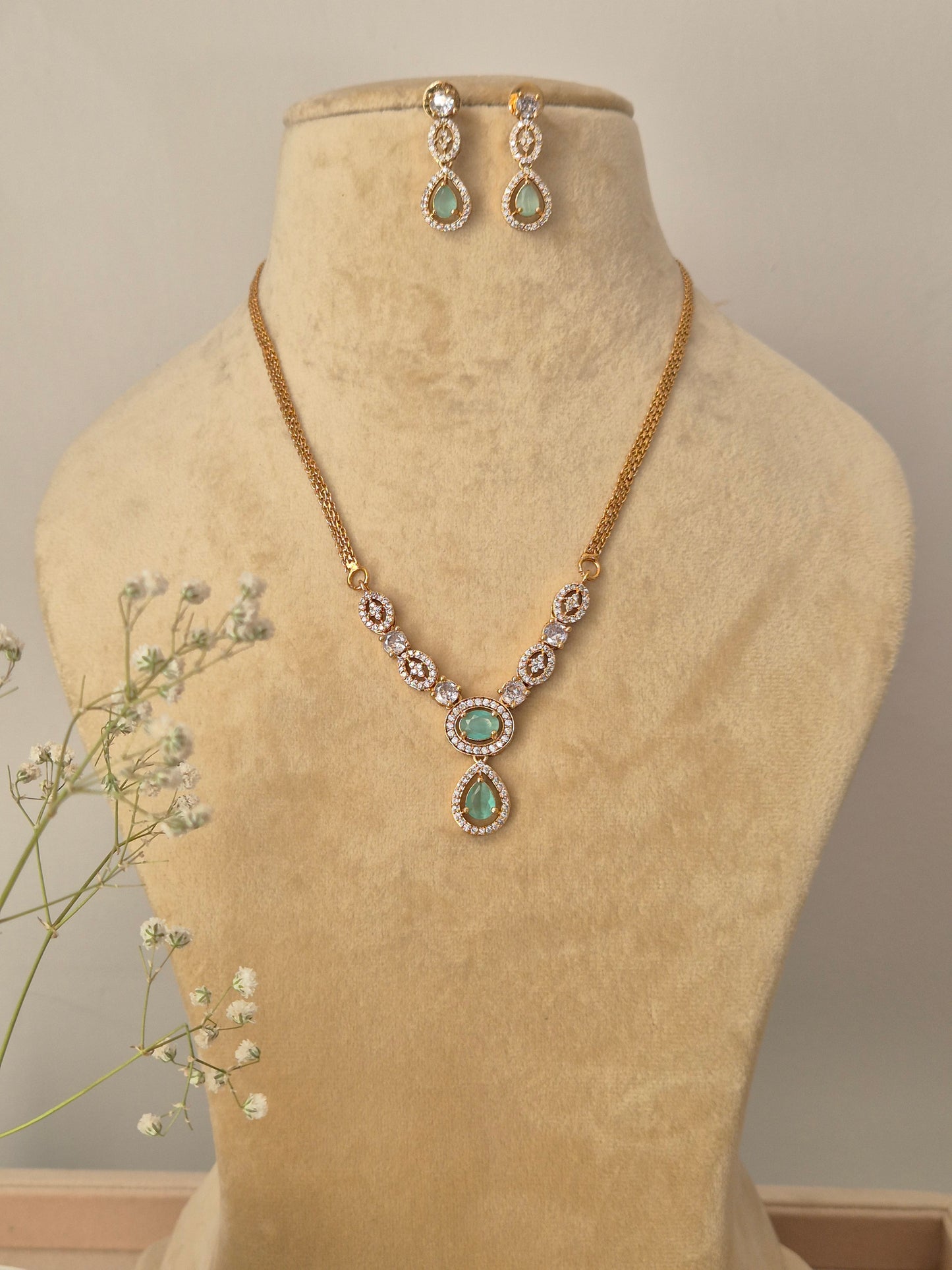Gold-plated brass chain necklace with mint green teardrop stone pendants and matching drop earrings by naitri.in