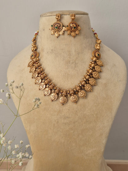 : Handcrafted gold-polished brass strand necklace featuring traditional coin charms, green and red stone accents, and matching round drop earrings by naitri.in