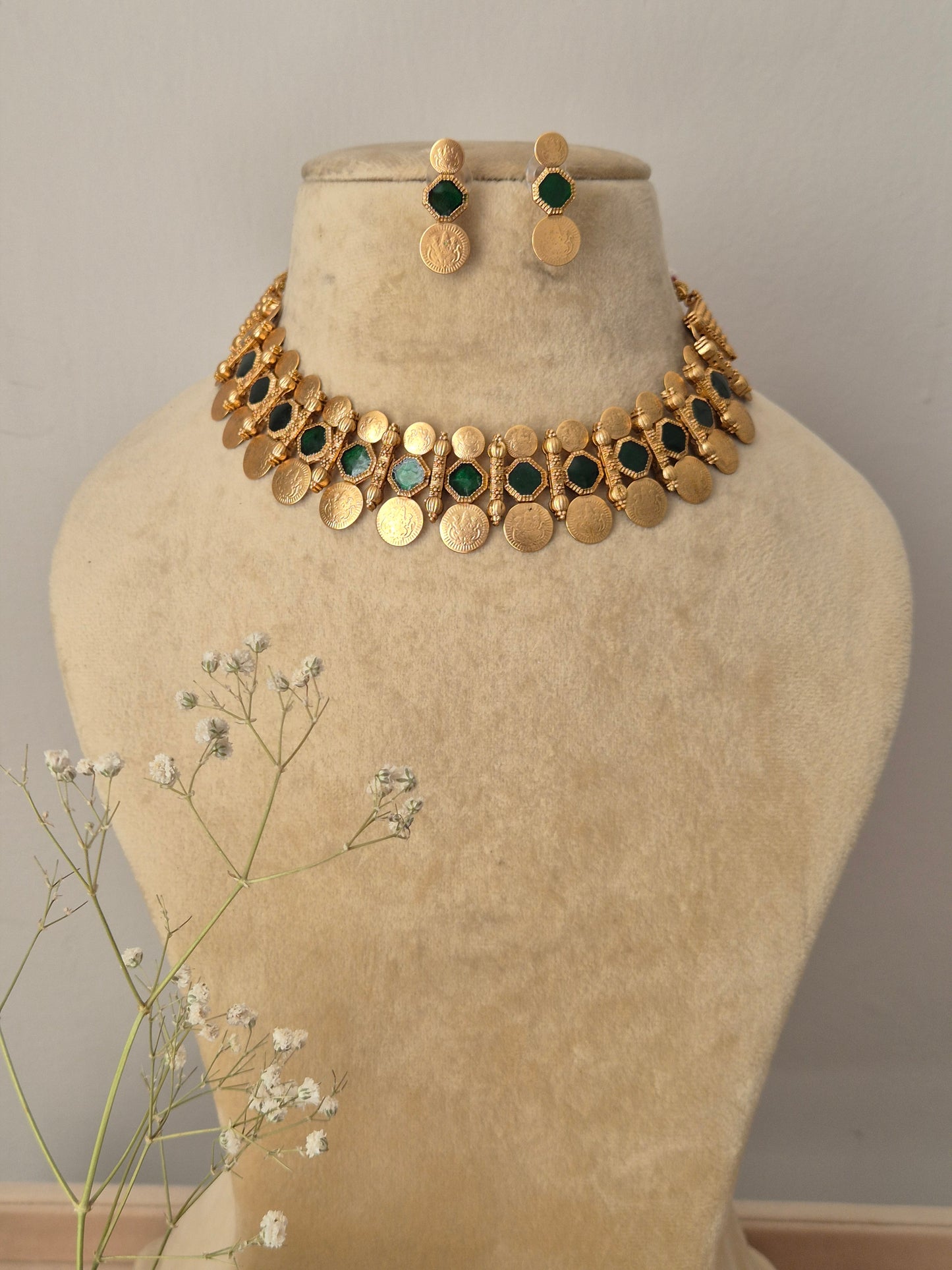 Handcrafted gold-polished brass choker necklace featuring alternating green stone accents and dangling round coin charms, with matching round gold stud earrings by naitri.in