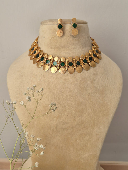 Handcrafted gold-polished brass choker necklace featuring alternating green stone accents and dangling round coin charms, with matching round gold stud earrings by naitri.in