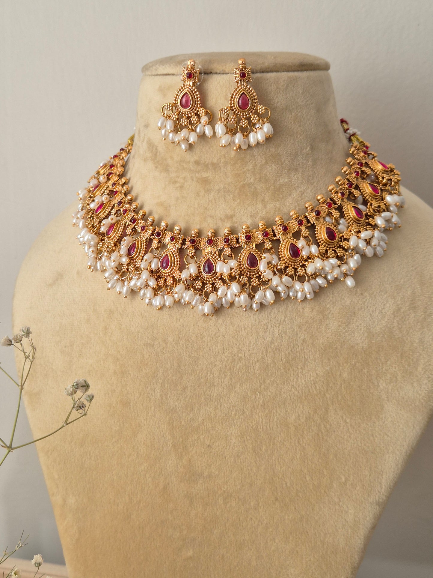 Handcrafted gold temple jewelry choker necklace and matching drop earrings with red stones and pearl cluster fringes by naitri.in