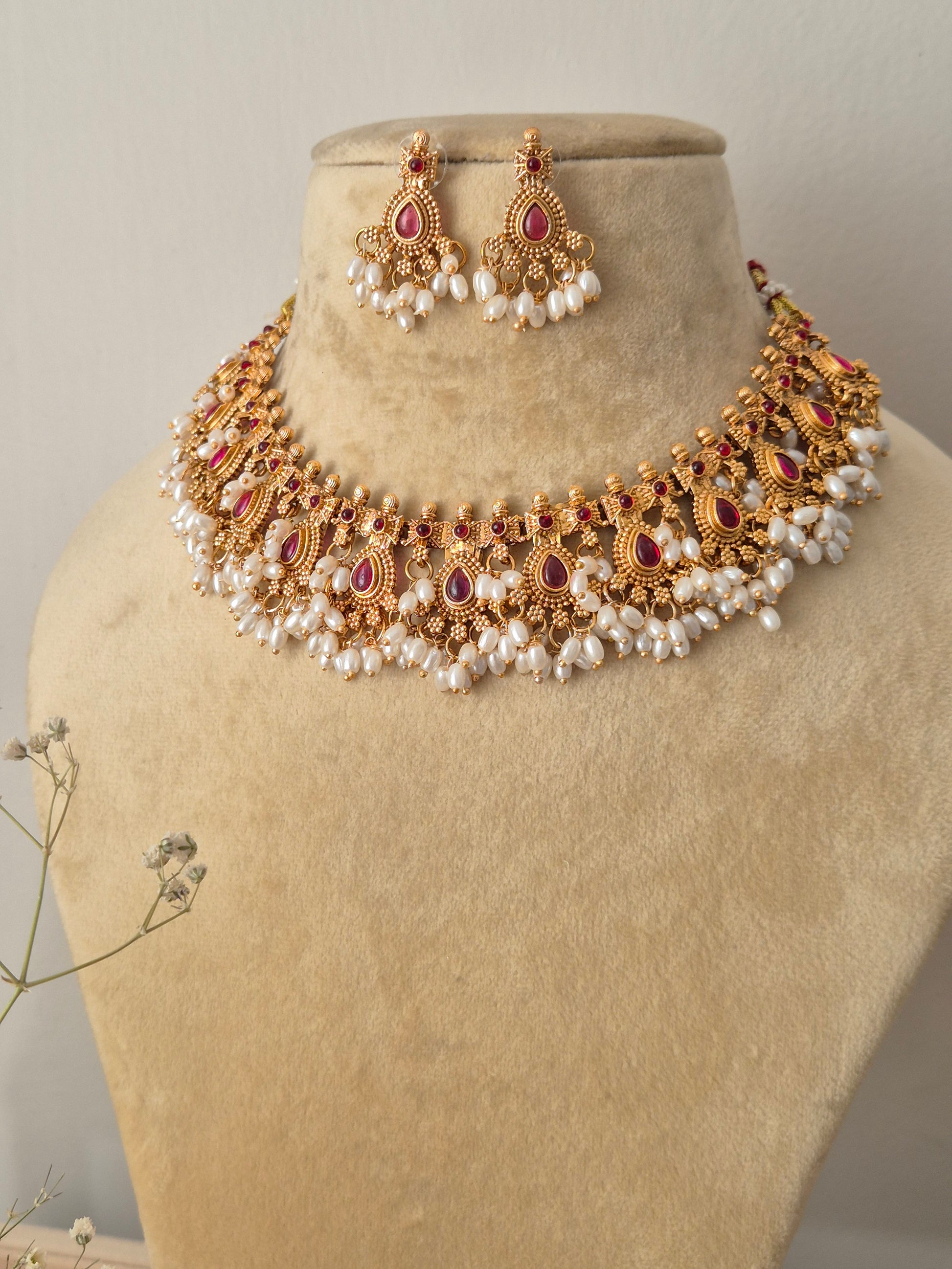 Handcrafted gold temple jewelry choker necklace and matching drop earrings with red stones and pearl cluster fringes by naitri.in