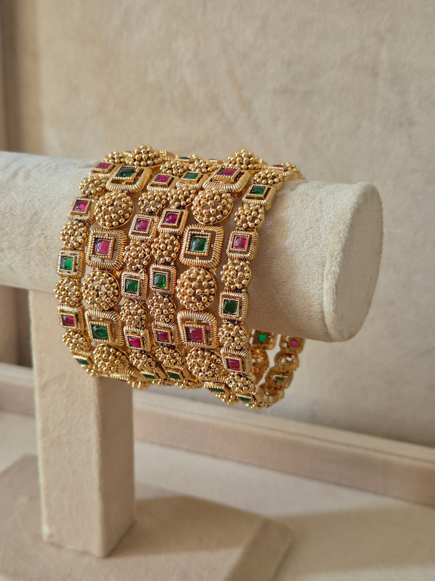 Set of six traditional gold-toned festive bangles with red and green gemstones.