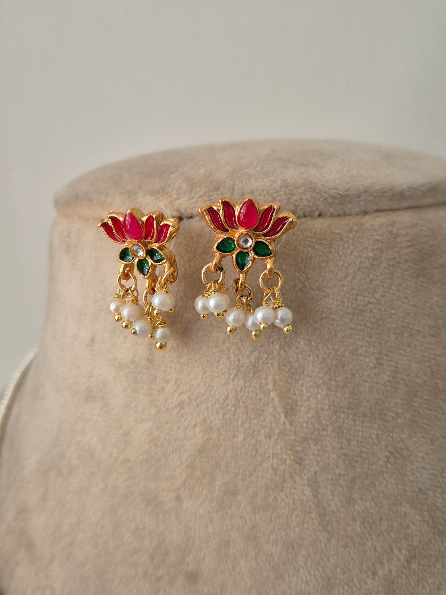 Pair of gold earrings with pink petals and green leaves and white pearls a small stone in the middle minimal and aesthetic design by naitri.in 